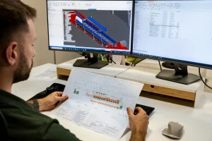 Tecnico confronta il disegno di layout e il modello 3D CAD di una linea modulare per ortofrutta